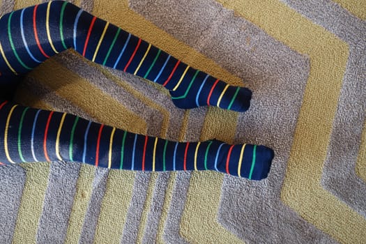 top view of child with Colorful striped socks sitting on carpet ,