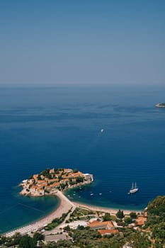 Sailboat sails past the island of Sveti Stefan. Montenegro. Top view. High quality photo