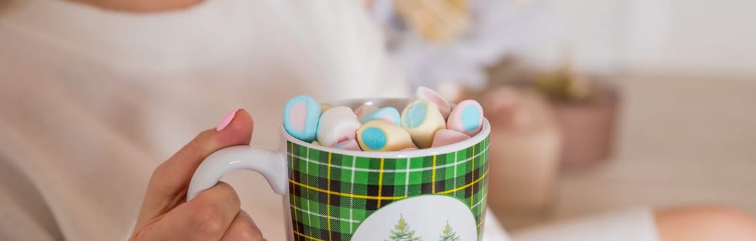 Close-up image, A tasty hot melted chocolate with tiny marshmallows cup in a woman's hand. Winter drinks concept
