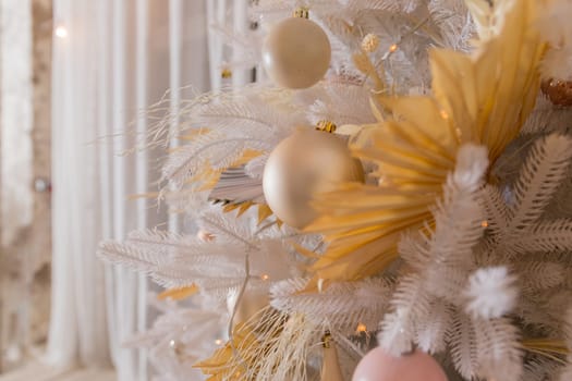 Close up of beautiful fir branches with shiny golden, silver and white baubles or balls, xmas ornaments and garland lights