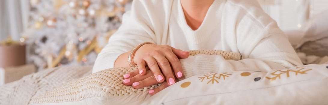 Female hand with beautiful natural manicure - pink nude nails on pale pink fluffy fabric, textile background