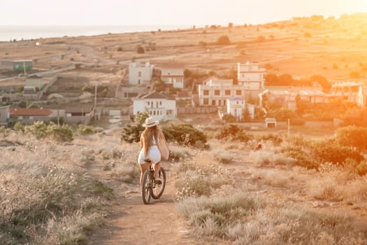 Woman travel bike. Happy woman cyclist sitting on her bike, enjoying the beautiful mountain and sea landscape, signifying the idea of an adventurous bike ride