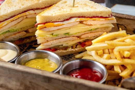 Chicken club sandwich with fries, ketchup, mustard and mayonnaise