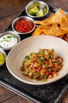Pico de gallo from Mexican cuisine with dipping sauces on wooden table