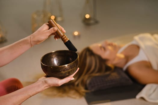 a girl lying on the floor relaxes to the sounds of a Tibetan bowl in the gym.