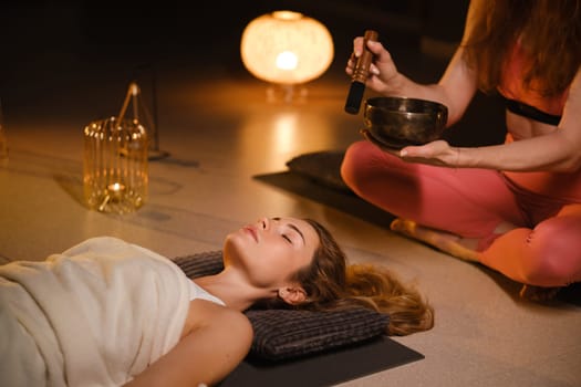 a girl lying on the floor relaxes to the sounds of a Tibetan bowl in the gym.