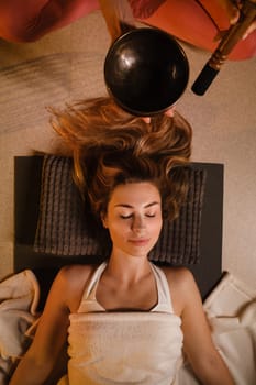 a girl lying on the floor relaxes to the sounds of a Tibetan bowl in the gym.