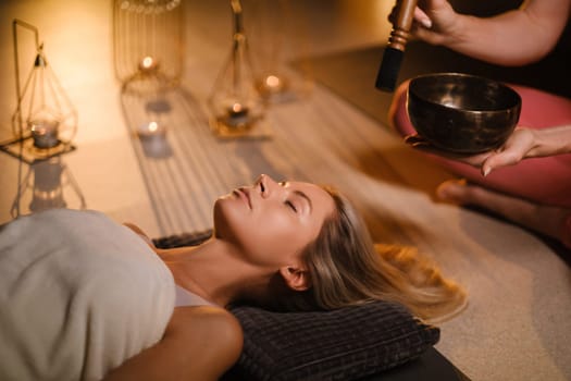 a girl lying on the floor relaxes to the sounds of a Tibetan bowl in the gym.