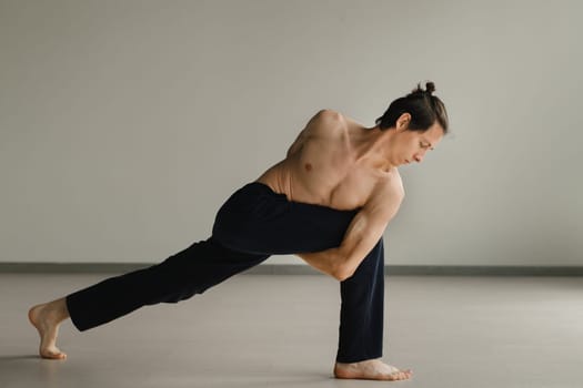a man with a naked torso does yoga in the gym. the concept of a healthy lifestyle.