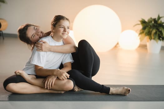 portrait of a mother and daughter of a teenager in sports clothes hugging, who are together in a fitness room. the concept of family sports.