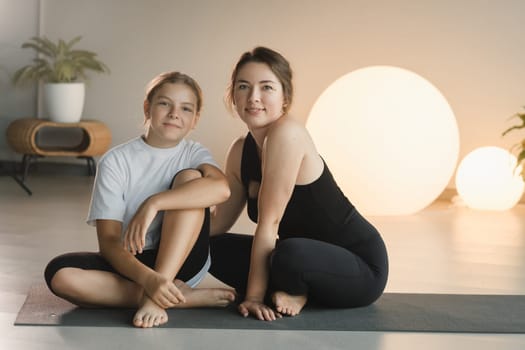 portrait of a mother and daughter of a teenager in sports clothes hugging, who are together in a fitness room. the concept of family sports.