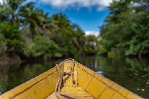 "Yellow canoe on tranquil river through greenery under blue sky."
