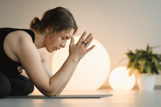 A girl in black sportswear does yoga on a mat in the fitness room.