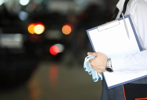 Auto mechanic and auto engineer technician holding clipboard blank sheet with copy space for car repair checklist. Car repair in car workshop