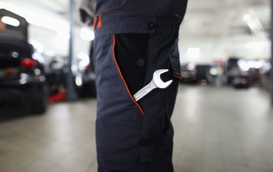 Wrench in pocket in uniform at locksmith in auto repair shop. Tool in special work clothes and car maintenance