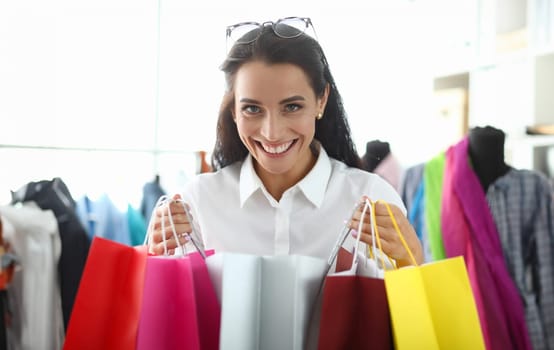 Satisfied happy woman with bright shopping bags buys packages and enjoys discounts. Girl smiling broadly showing bought gifts for holidays sale concept