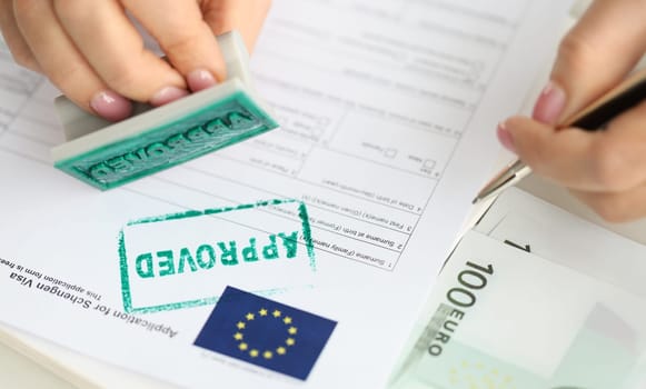 Approval of visa for travel to European Union, an employee of embassy puts stamp. Getting Schengen visa concept