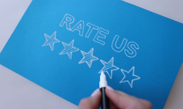 Handwritten review rate us and star rating on blue background. Customer feedback and service recommendation concept