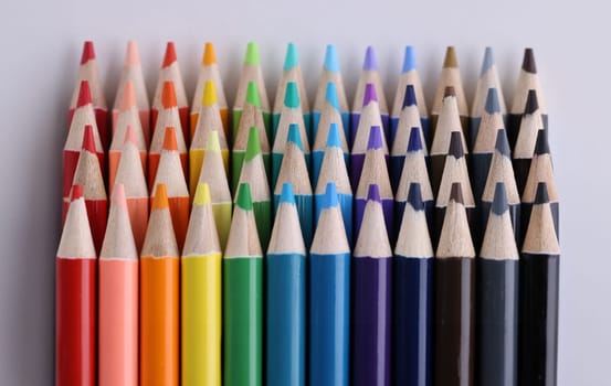 Set of multicolored pencils lying on white table in row. Creativity variou of possibilities and play of imagination and fantasy make the world bright and impressive