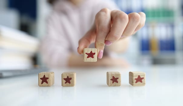Hand holds cube made of wooden blocks in shape of five red stars. Best concept of customer experience evaluation