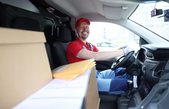 Smiling courier sits in car as driver. Logistics and delivery of goods concept