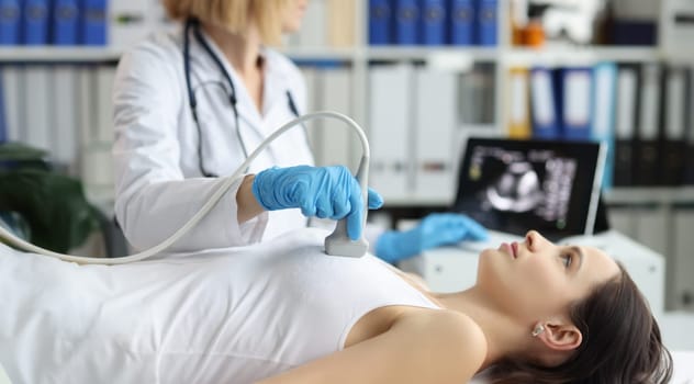 Doctor holds ultrasound probe on chest of patient in clinic closeup. Medical examination of breast in clinic