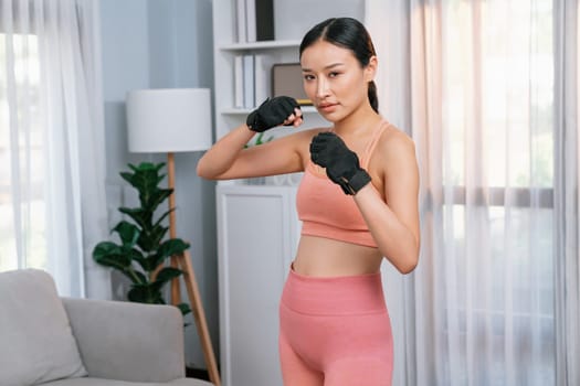 Fit young asian woman portrait in sportswear preparing herself before healthy exercising routine at home. Domestic fitness workout training on living room. Vigorous