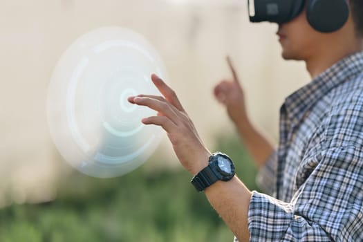 Young farmer wearing visual reality glasses in field. Smart farming and agricultural innovation concept.