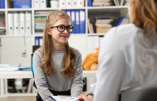 Portrait of smiling girl in glasses at doctor appointment. Services and consultation of pediatrist concept