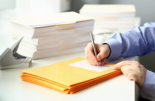 Businessman is preparing parcel for delivery at table in office. Sending business correspondence concept