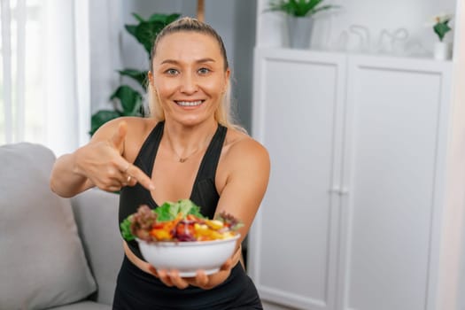 Healthy senior woman in sportswear holding a bowl of fruit and vegetable. Vegan lifestyle and healthy cuisine nutrition for fitness body physique concept. Clout