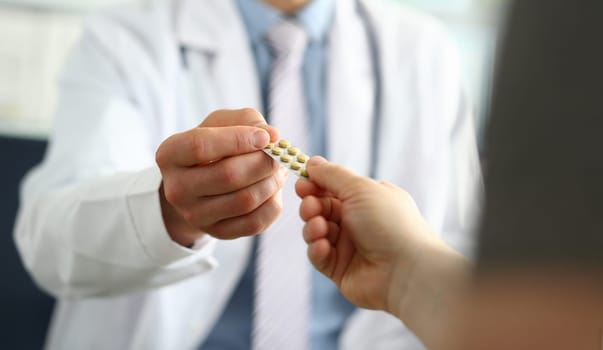 Closeup of doctor hand giving medical pills to patient. Prescribing medications to patient in illness concept