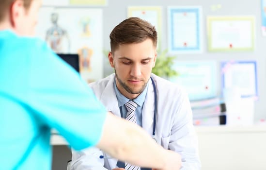 Doctor talks and listens to patient in clinic. Male conversation with urologist concept