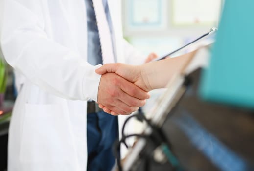 Doctor and patient shake hands in clinic. Medical care contract and insurance with handshake