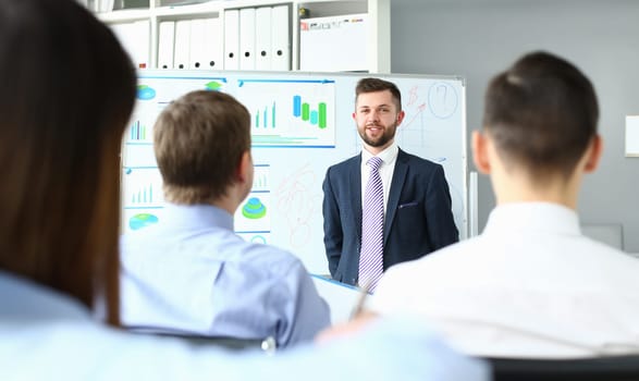 Male mentor coach conducts training on financial investment. Business goals presented to group of investors at a conference