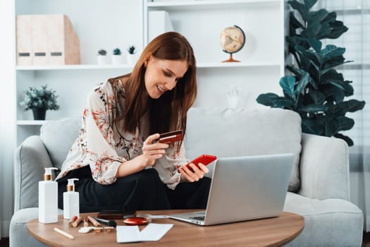 Young happy woman buy product by online shopping at home while ordering items from the internet with credit card online payment system protected by utmost cyber security from online store platform