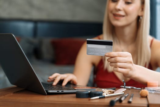 Young woman using laptop with credit card for internet banking, online shopping E commerce by online payment gateway at home office. Modern and convenience online purchasing with debit card. Blithe