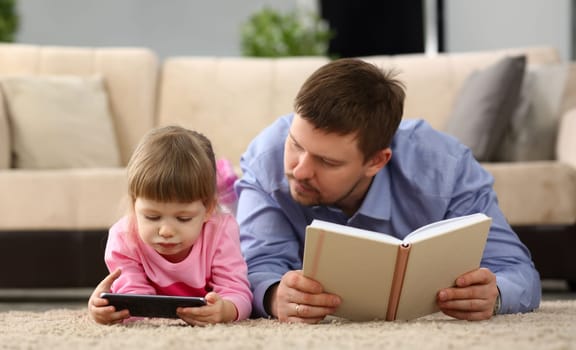 No more communication in family and dependence of children on gadgets. Dad holding book child is staring at smartphone screen