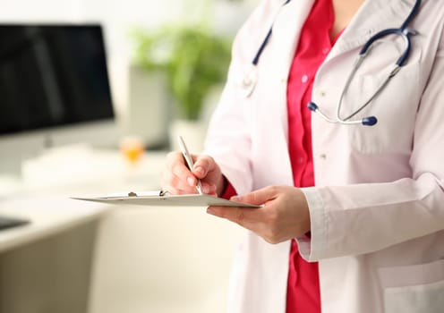 Woman medicine doctor with silver pen writes on a clipboard closeup. Medical calculation and statistics and insurance concept