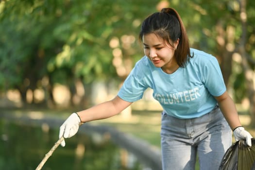 Volunteer young woman collecting garbage in the park. Environmental protection concept.