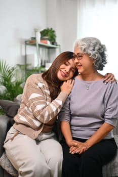 Smiling Asian woman embracing mature mother expressing unconditional love.