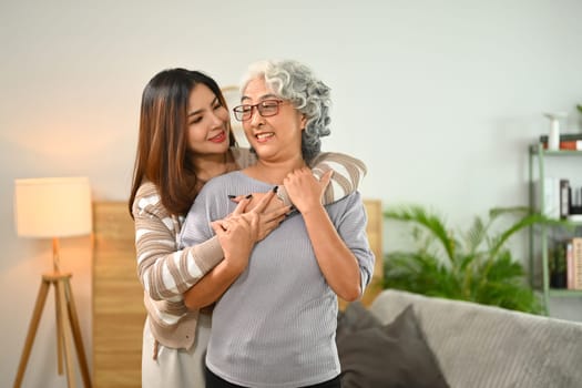 Loving adult daughter hugging mature mother from back showing love and support.