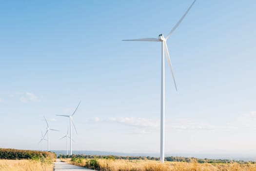 On a mountain farm windmill turbines symbolize clean energy innovation. Sustainable development thrives with modern wind technology against the backdrop of a blue sky.