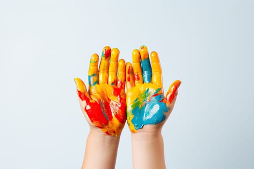 Child's hands in multi-colored paints on a white background.