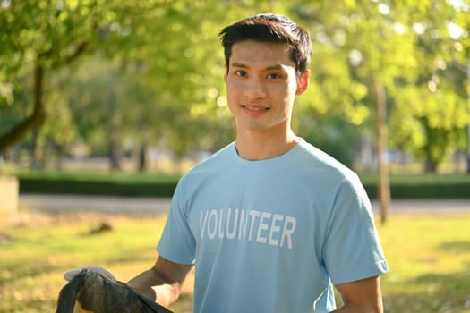 Portrait of male volunteer cleaning up and separating garbage at outdoor. World Environment Day concept.