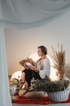 Women's circle and practice in the use of metaphorical cards. The girl is sitting surrounded by flowers.