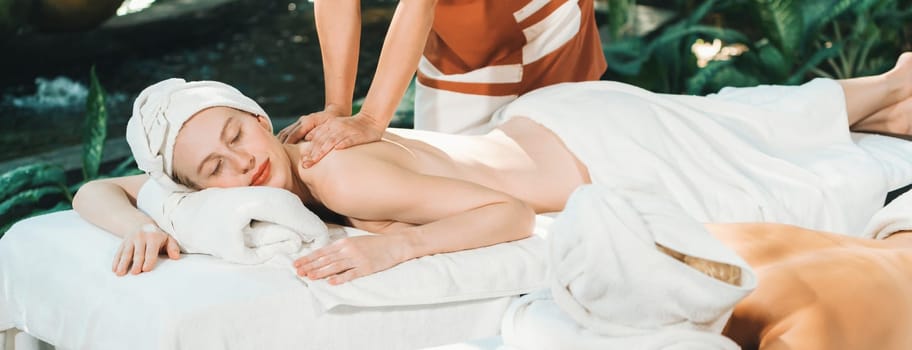 Couple of beautiful young woman lie on white spa bed during having back massage. Attractive caucasian woman having back massage at traditional spa room. Relaxing and healthy concept Tranquility.