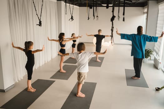 Children do yoga in the gym under the guidance of an instructor. Children's gymnastics.