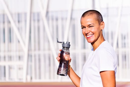 happy young sports woman smiling looking at camera and drinking water during training, concept of healthy and active lifestyle, copy space for text