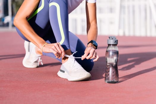 unrecognizable sporty woman tying her running shoes before her workout, concept of healthy and active lifestyle